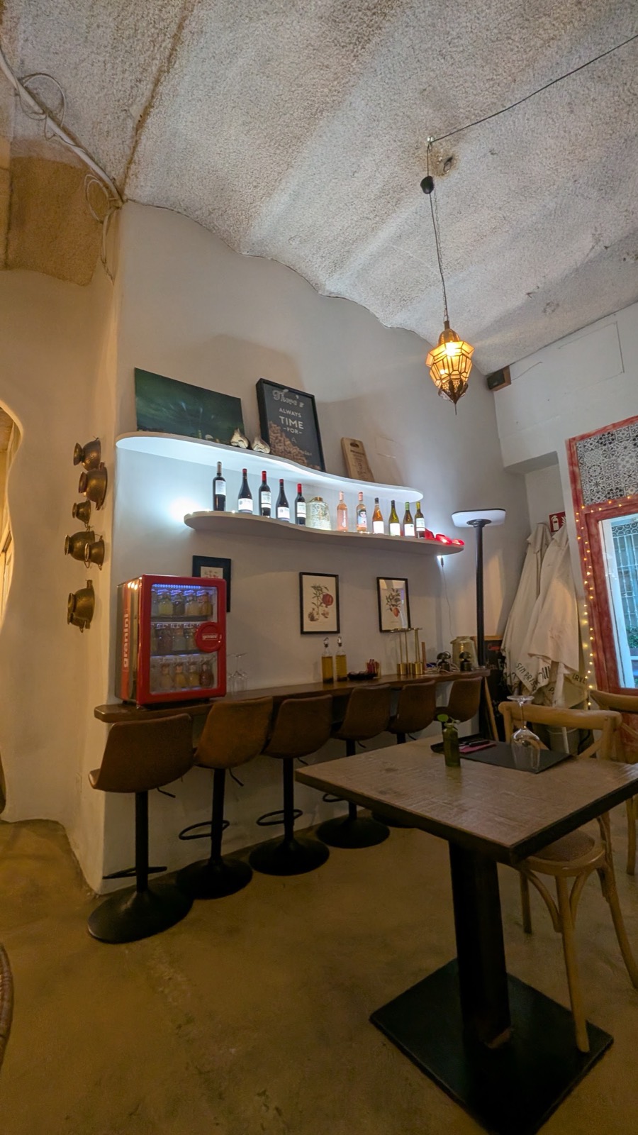 El interior de La Taula de Papel: barra con taburetes, techo de bóveda y lámparas
